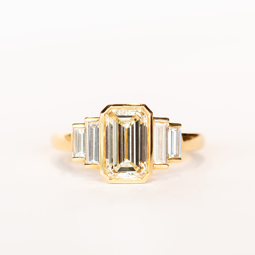 A yellow gold, emerald cut diamond engagement ring with baguette cut side stones.