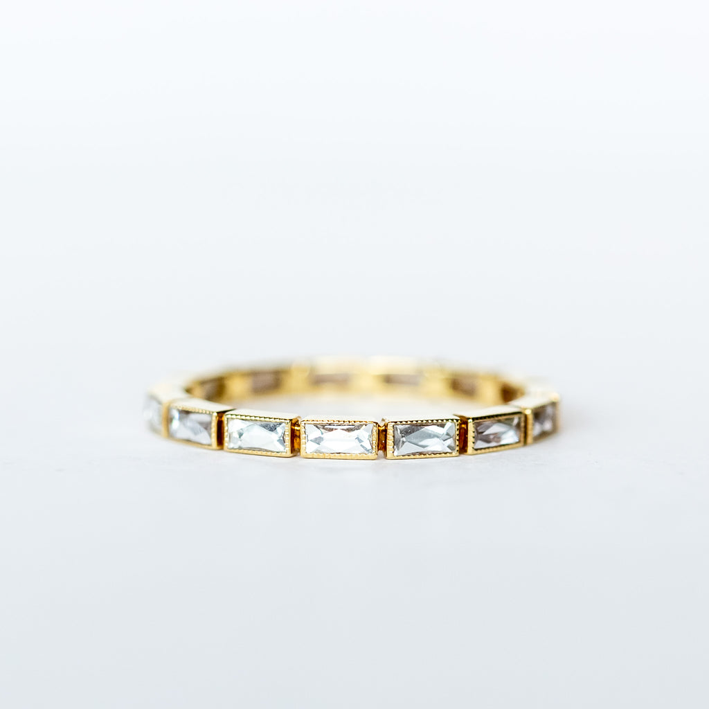 A yellow gold eternity band made up of bezel set, rectangular French cut diamonds.