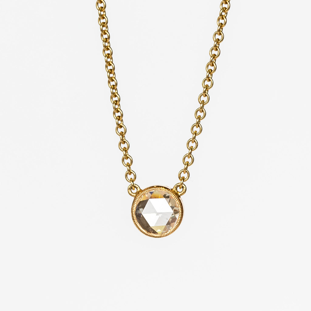 A round rose cut diamond bezel set in a station style necklace with classic gold cable chain.