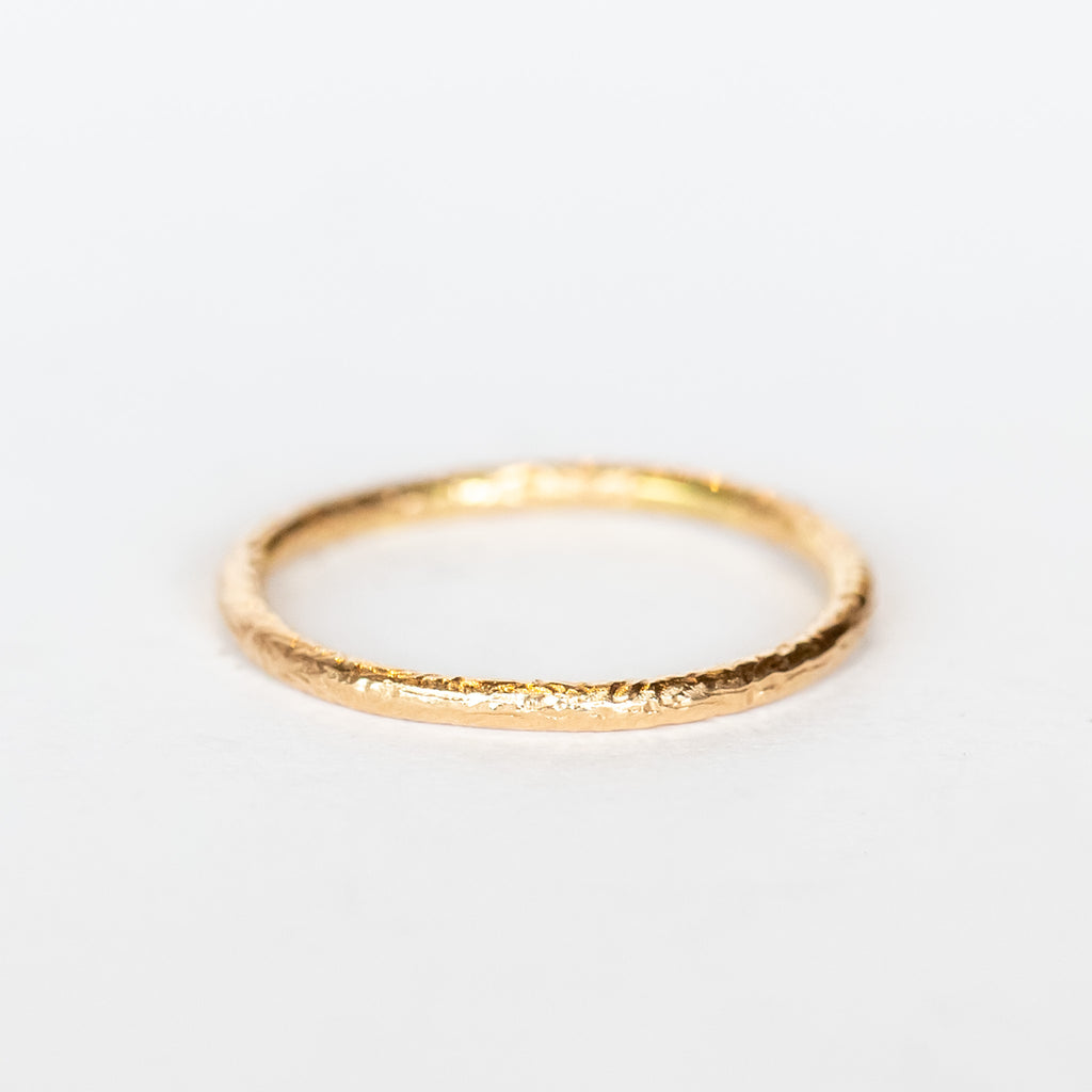 A thin, textured rose gold wedding band.