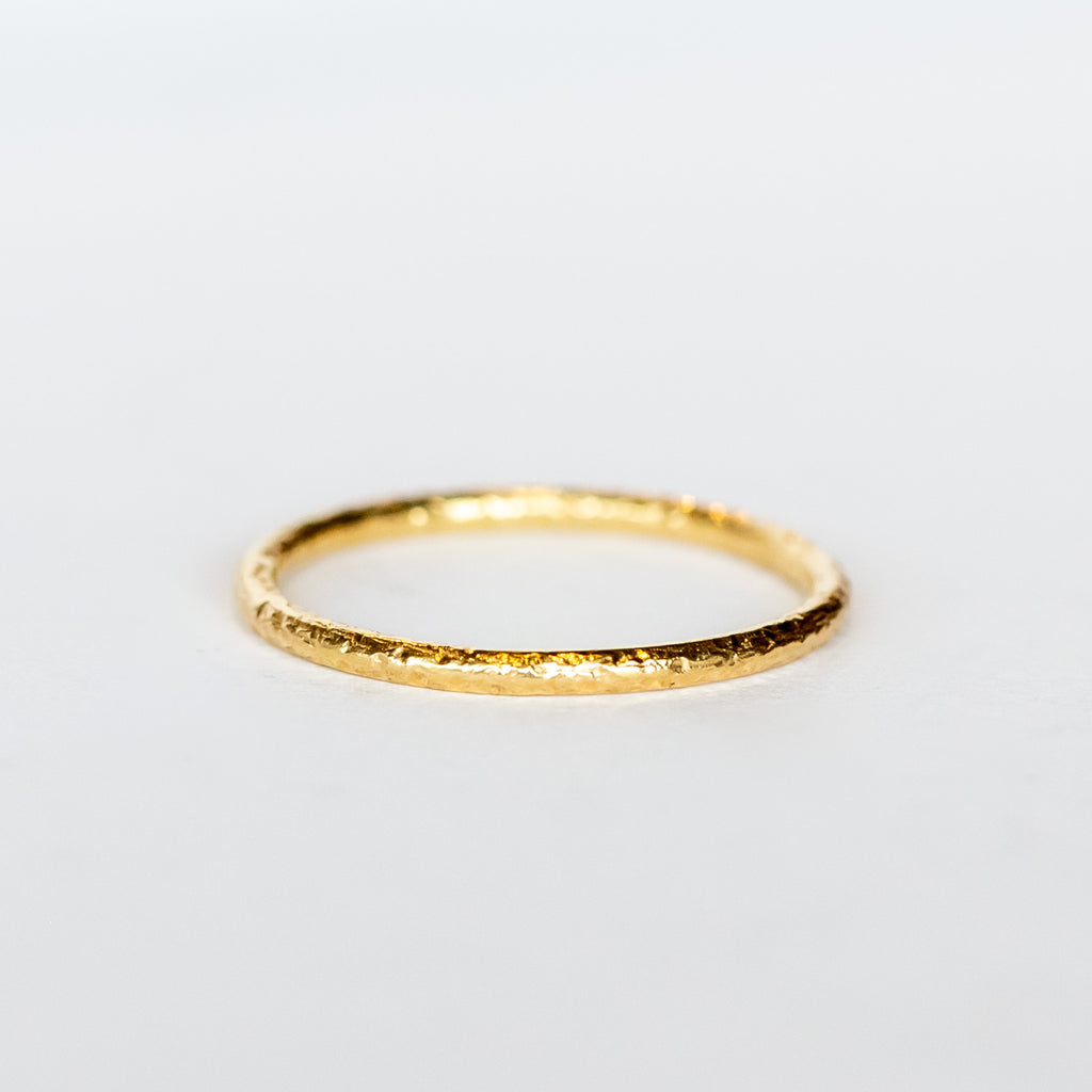 A hammered texture, thin yellow gold wedding band.
