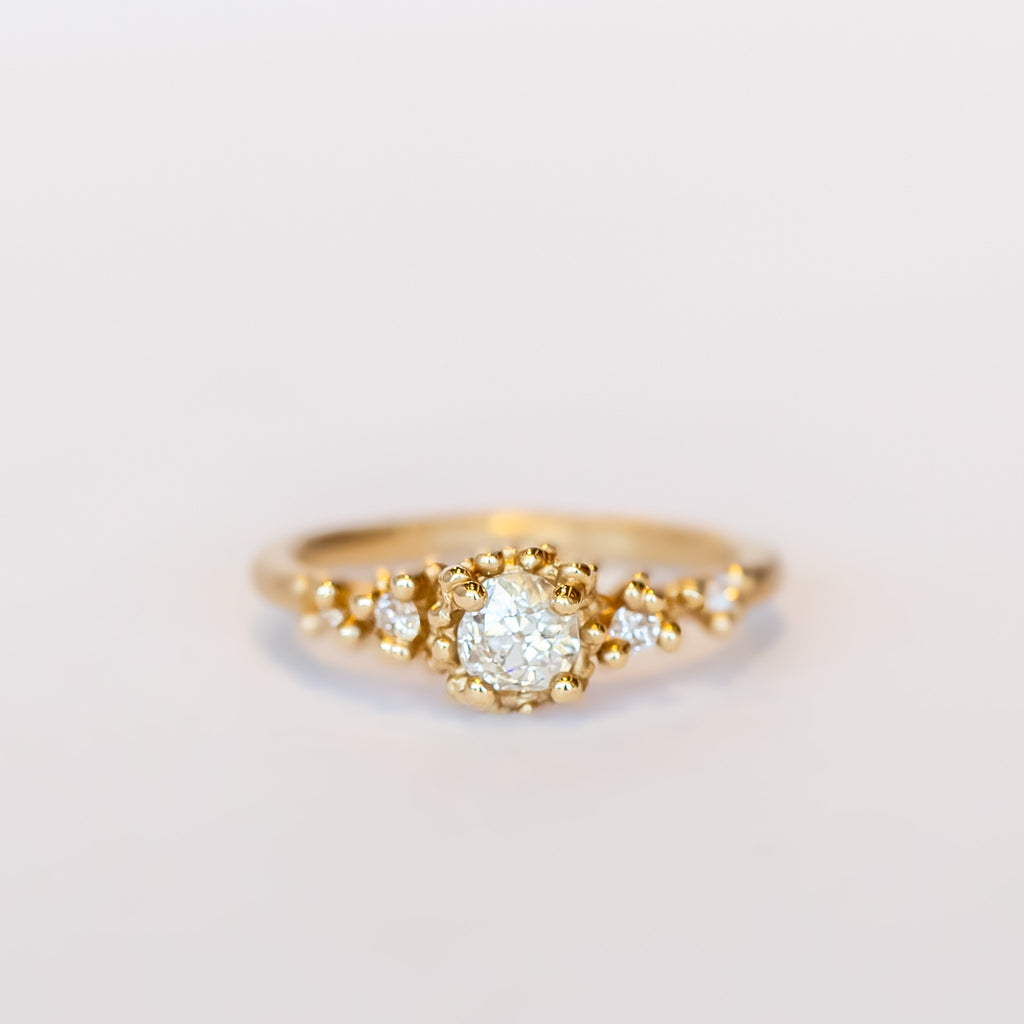 Unique antique cut diamond engagement ring with golden granules, on a gently textured band.