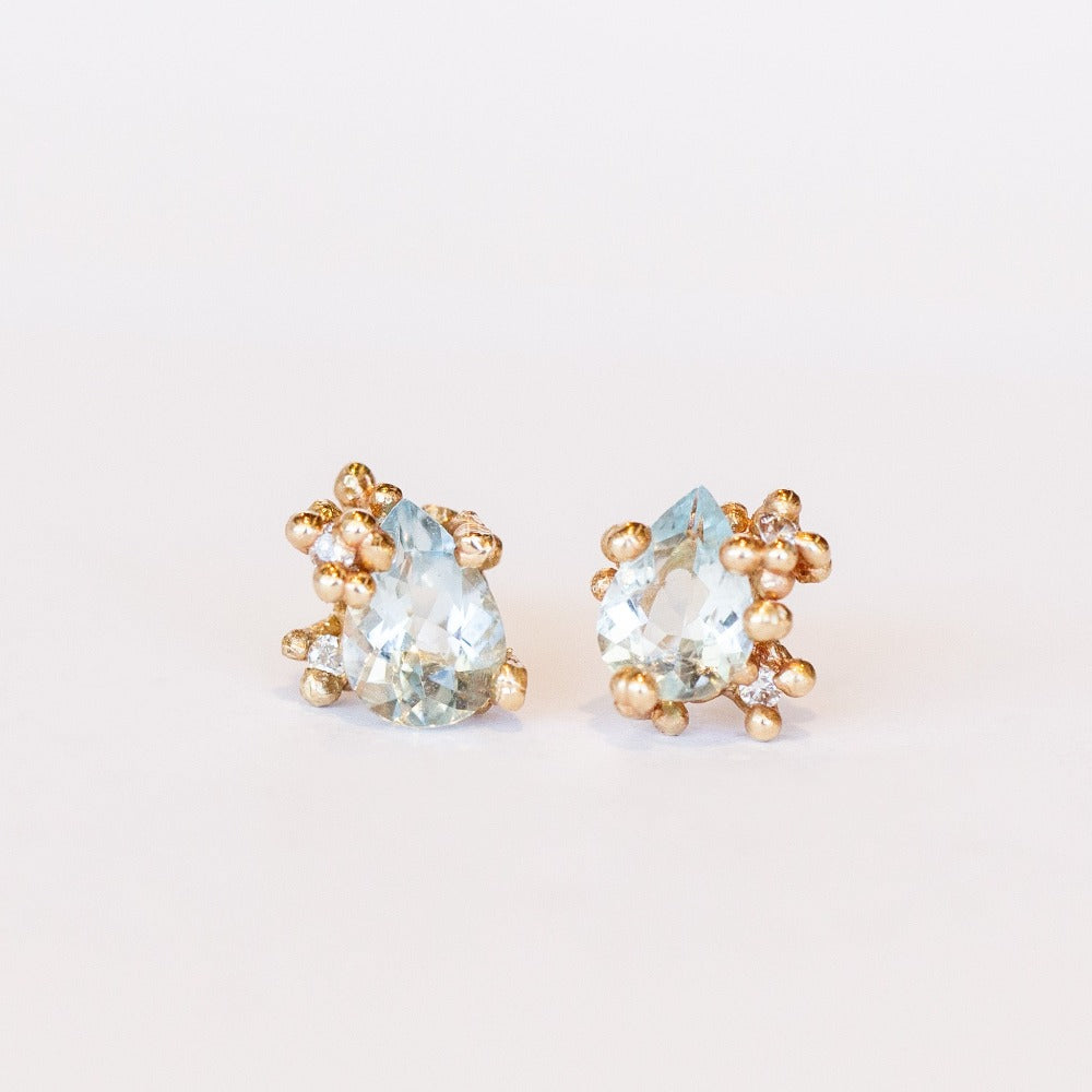 Gold stud earrings set with pear shaped aquamarines accented by tiny diamonds in gold granules.