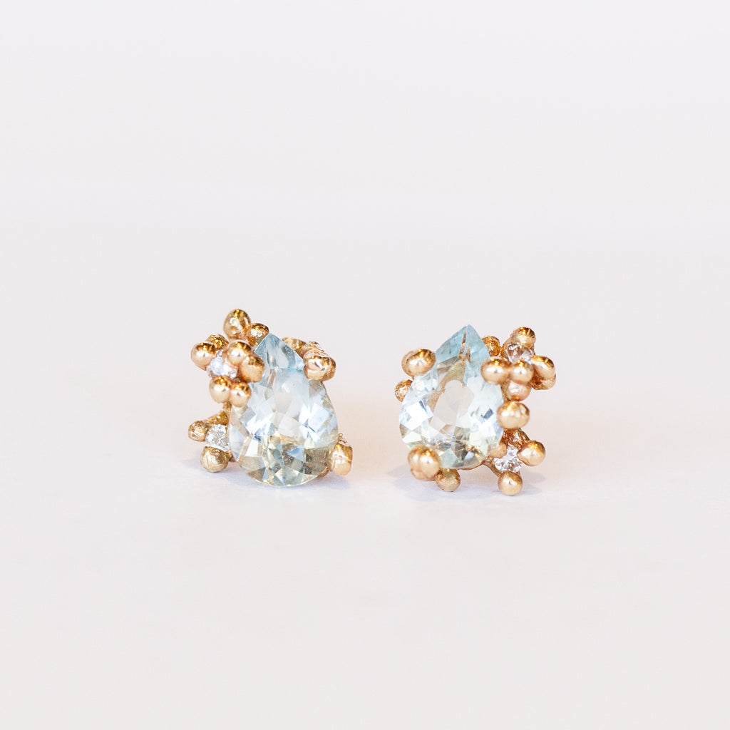 Gold stud earrings set with pear shaped aquamarines accented by tiny diamonds in gold granules.