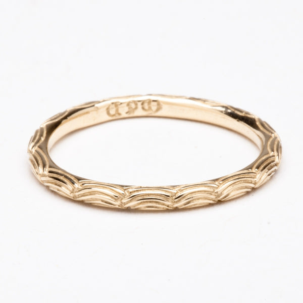 A dainty gold band with an intricate wave pattern all the way around.