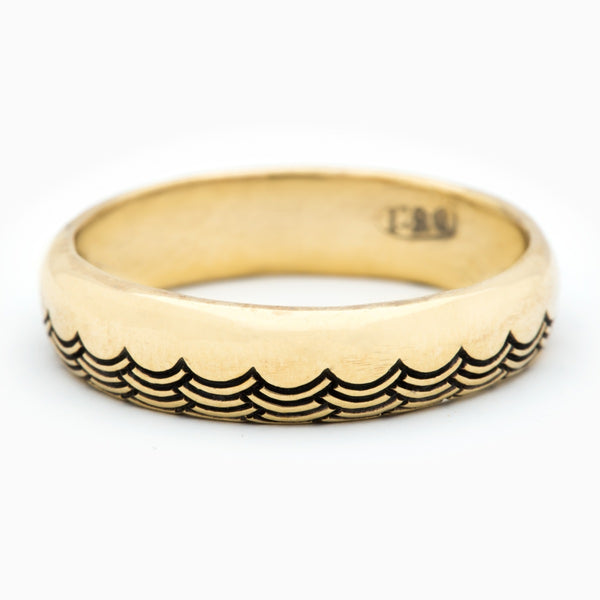 A 5mm half-dome gold band with a wave pattern engraving along one edge that wraps around the entire band.