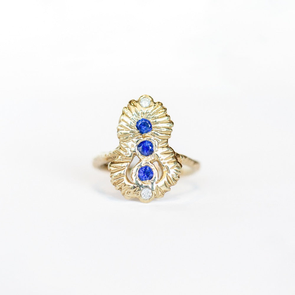 Top view of a Communion by Joy ring, hand carved from 14 karat yellow gold, it is set with three deep blue round sapphires and two white diamonds. 