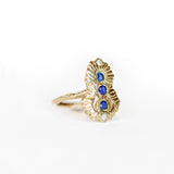 Side view of a Communion by Joy ring, hand carved from 14 karat yellow gold, it is set with three deep blue round sapphires and two white diamonds. 