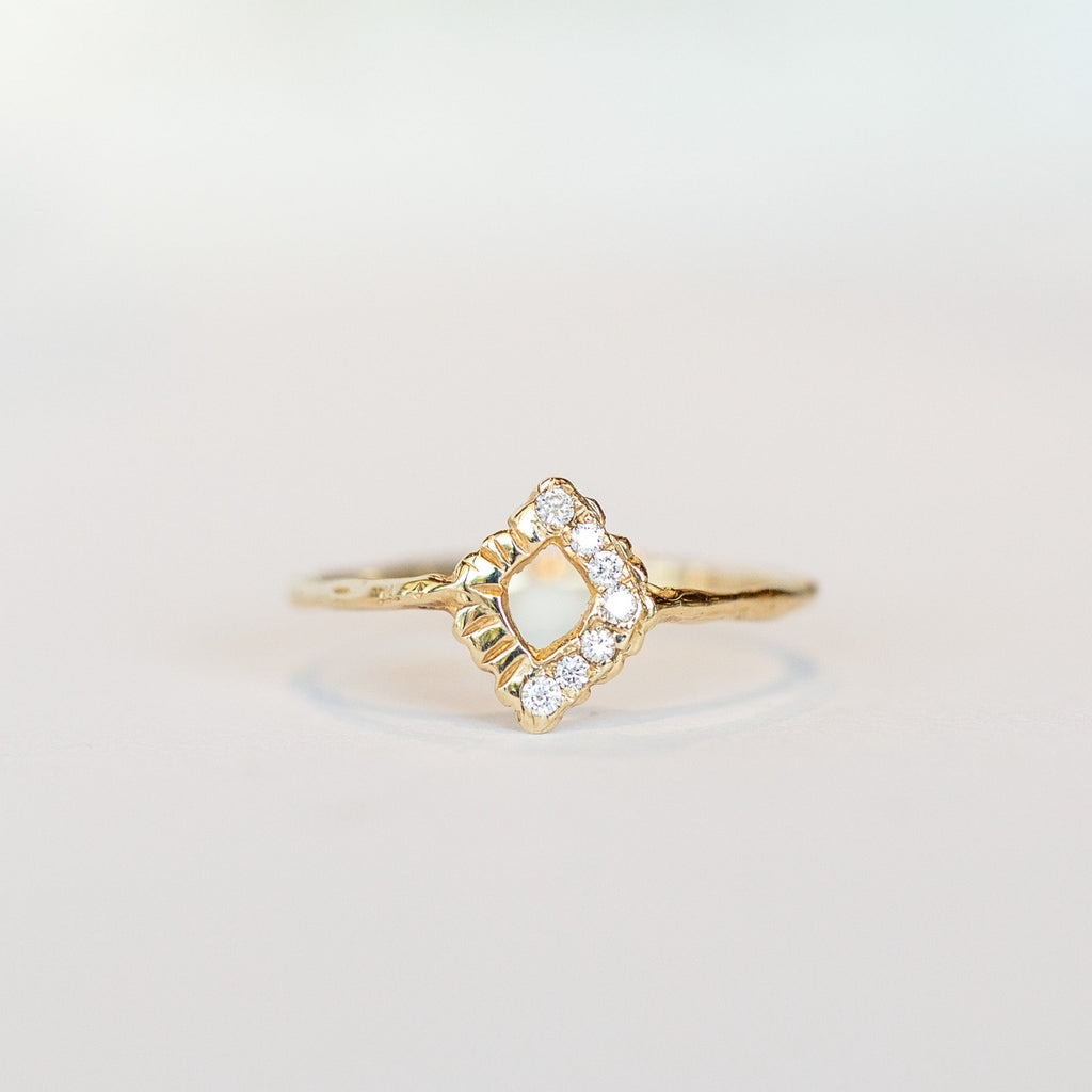 A thin, textured yellow gold ring with an open diamond-shaped top that has tiny diamonds along two of its four sides.