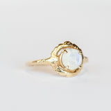 A hand carved yellow gold Communion by Joy ring featuring a thin band set with a faceted round moonstone.