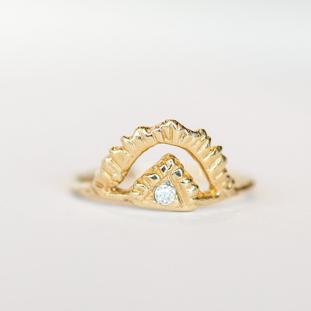 Top view of Communion by Joy ring. It's made of hand carved yellow gold, featuring an open pyramid shape on top, with one tiny diamond at the center, and a thin gold band.