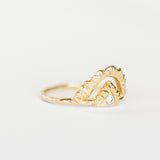 Slight side view of Communion by Joy ring. It's made of hand carved yellow gold, featuring an open pyramid shape on top, with one tiny diamond at the center, and a thin gold band.