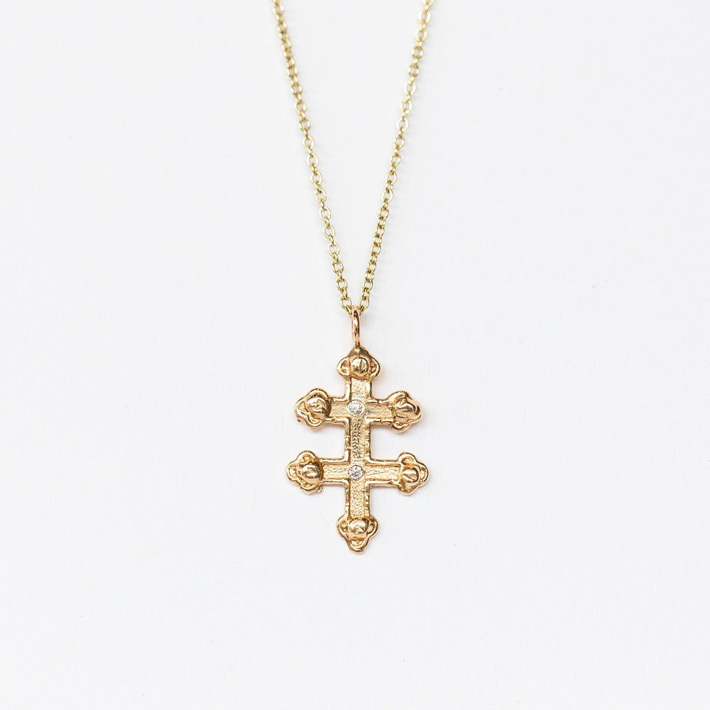 A hand carved yellow gold cross pendant with delicate diamond details from Communion by Joy.