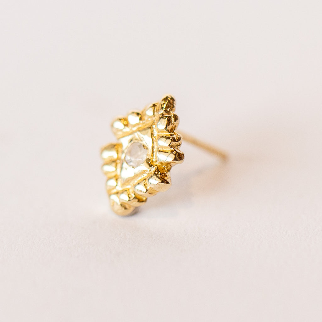 A pair of hand carved, diamond shaped yellow gold stud earrings from Communion by Joy, featuring small white moonstones.