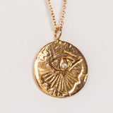 A carved eye medallion necklace with a petite diamond set in rose gold from Communion by Joy.