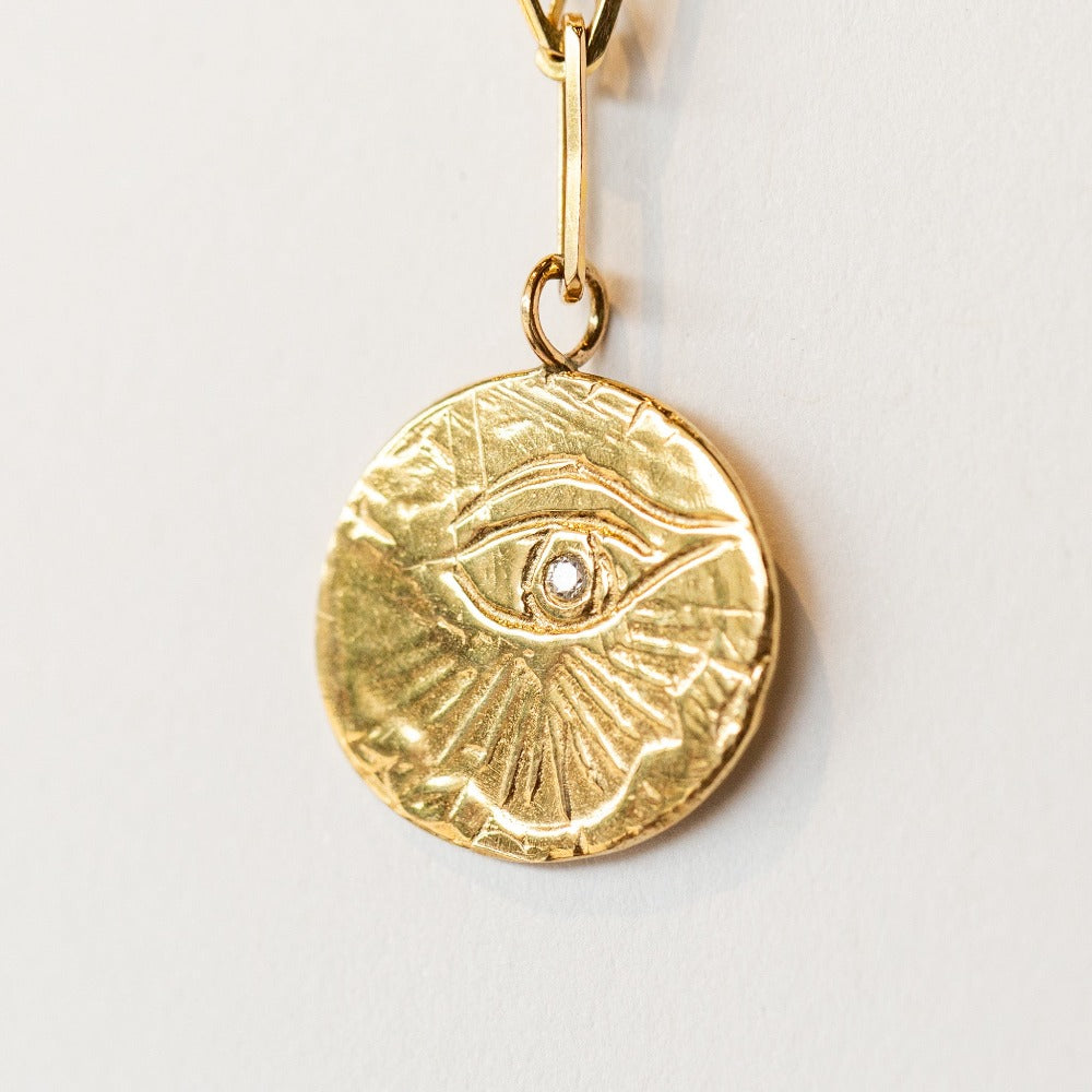 In this Communion by Joy bracelet, a hand-carved eye of love medallion hangs from an on-trend paperclip chain bracelet in 14 karat yellow gold. It's set with a single diamond.
