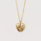 A hand carved gold heart pendant from Communion by Joy featuring a dove and tiny white diamond.