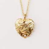 A hand carved gold heart pendant from Communion by Joy featuring a dove and tiny white diamond.