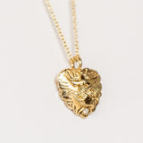 A hand carved gold heart pendant from Communion by Joy featuring a dove and tiny white diamond.