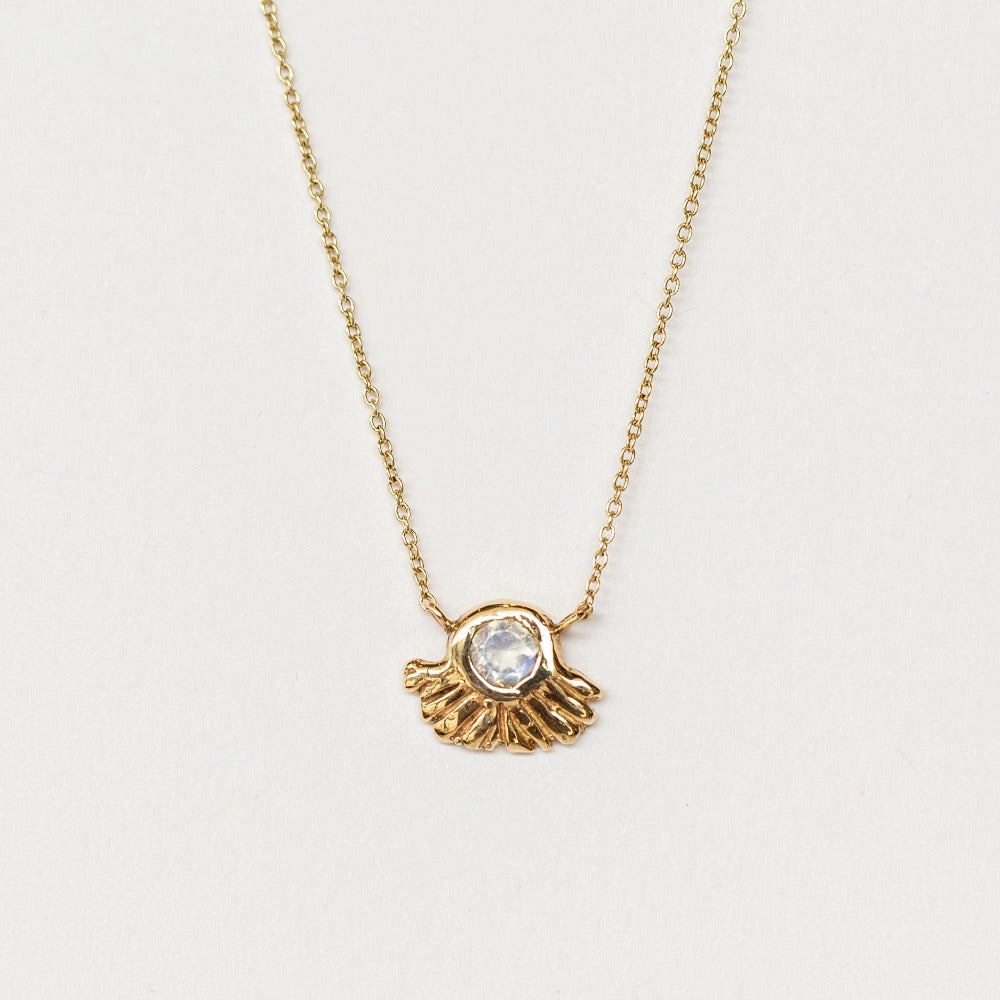 A carved gold pendant set with rainbow moonstone from Communion by Joy.