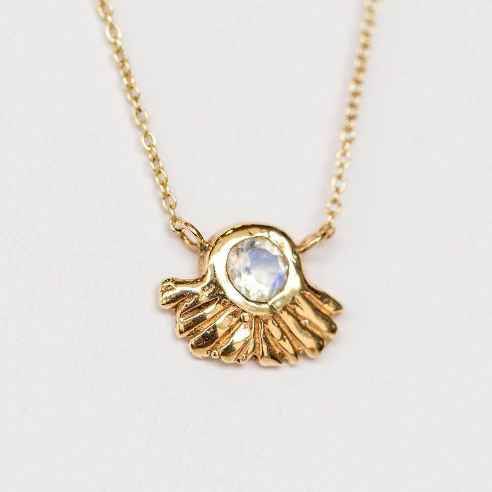 A carved gold pendant set with rainbow moonstone from Communion by Joy.