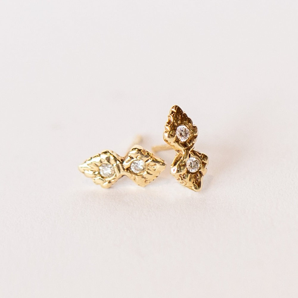 A pair of hand carved yellow gold stud earrings set with four small diamonds from Communion by Joy.