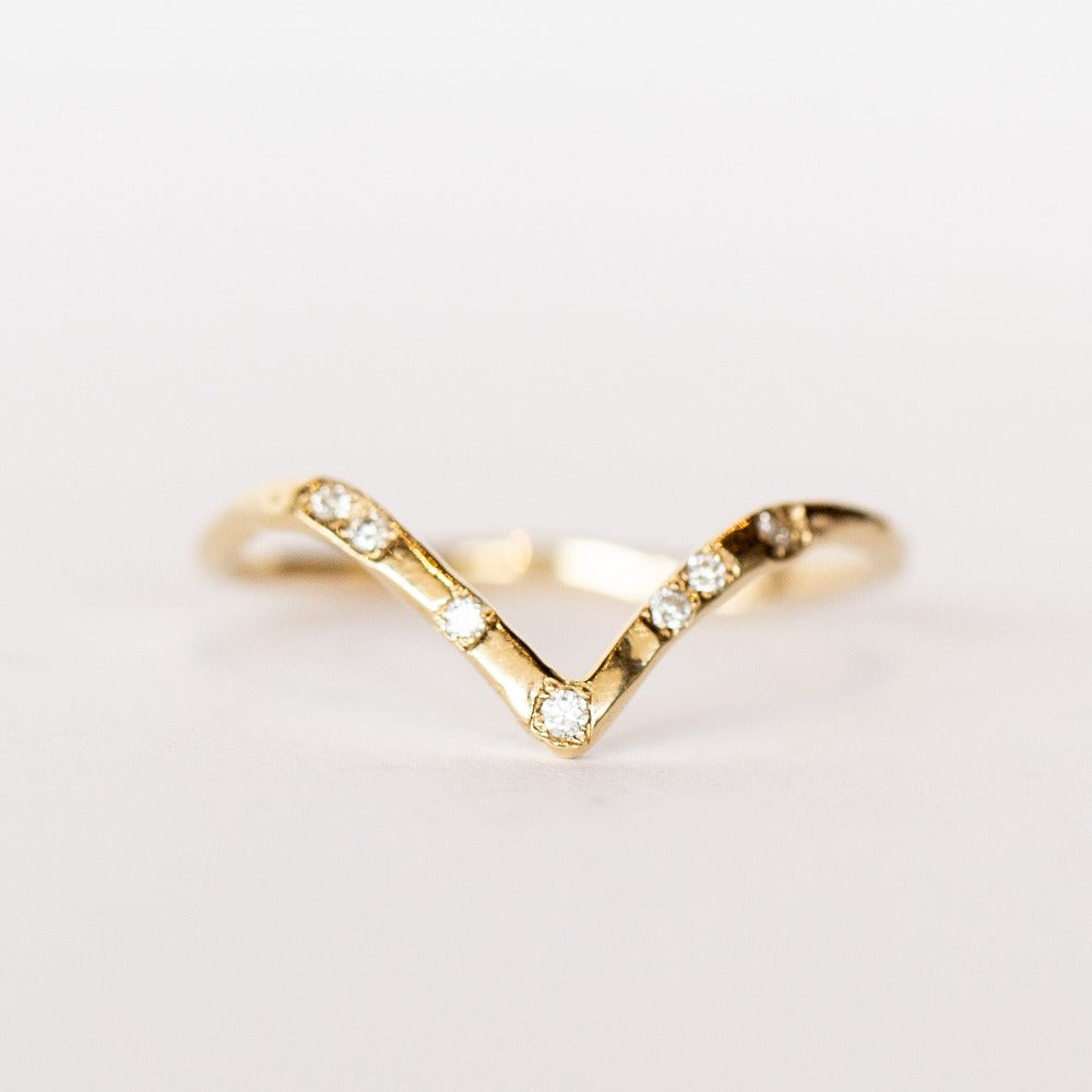Front view of a delicate, peaked contour band from Communion by Joy. It's made of hand carved yellow gold set with seven spaced out white diamonds.