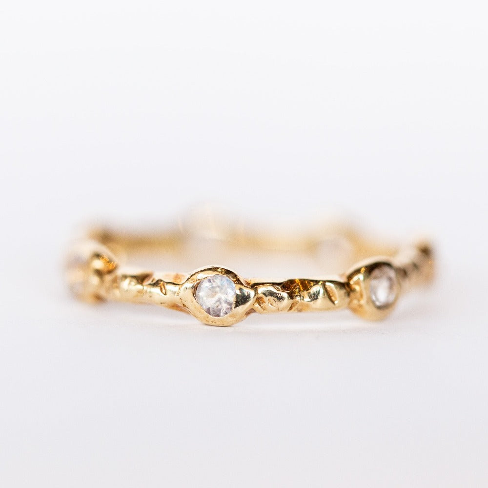 Close up view of Communion by Joy eternity band, seven petite faceted moonstone gems are set in hand carved details.