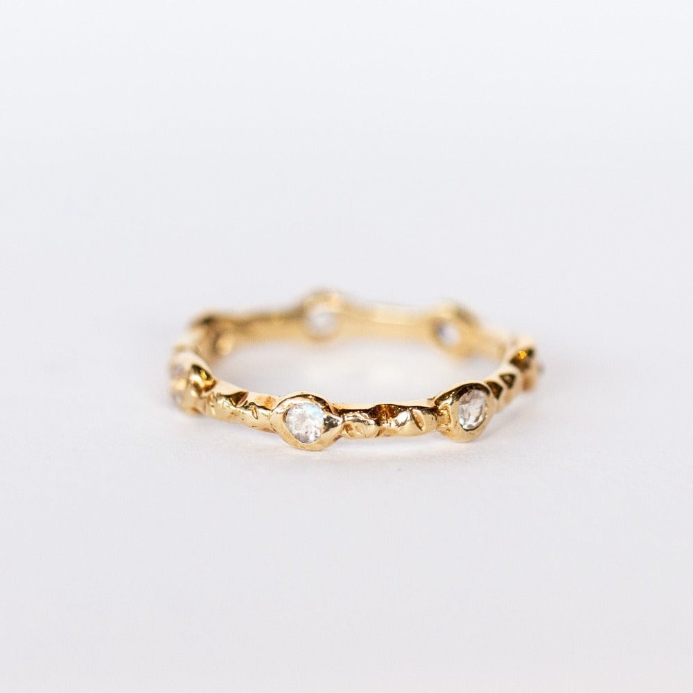 Side view of Communion by Joy eternity band, seven petite faceted moonstone gems are set in hand carved details.