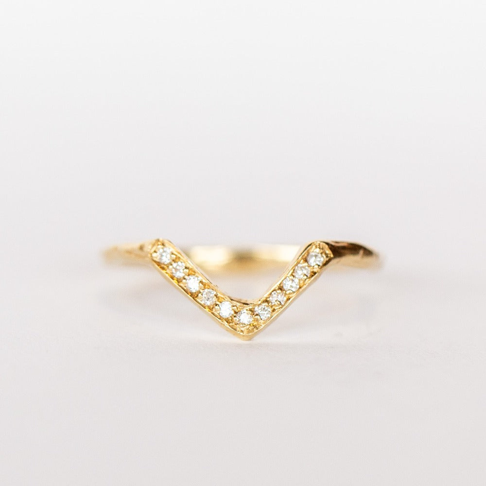 A yellow gold contour band from Communion by Joy, in a triangular peaked design, set with tiny white pave diamonds.