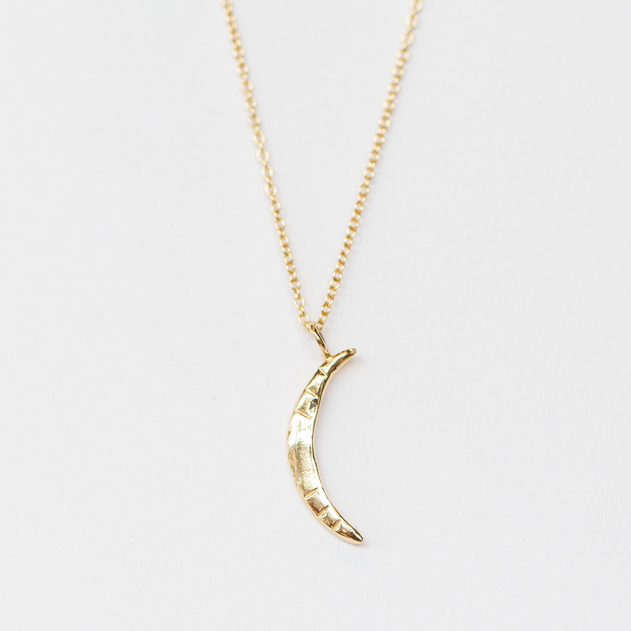 A carved gold crescent moon pendant from Communion by Joy.