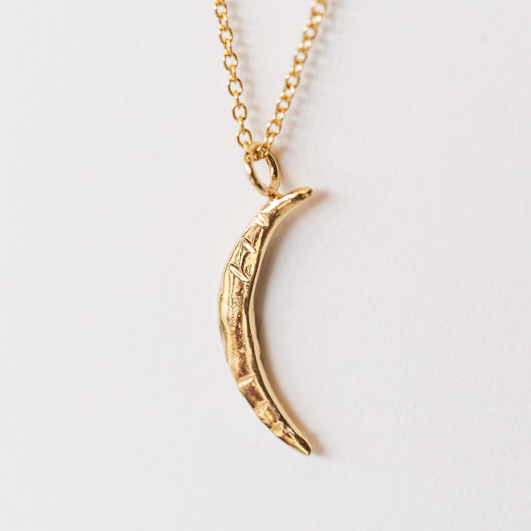 A carved gold crescent moon pendant from Communion by Joy.