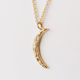 A carved gold crescent moon pendant from Communion by Joy.