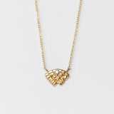 Small carved yellow gold necklace with a tiny diamond from Communion by Joy.