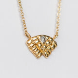 Small carved yellow gold necklace with a tiny diamond from Communion by Joy.