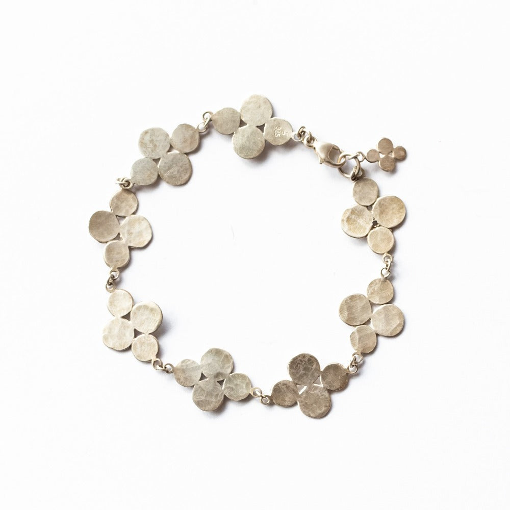 A chain bracelet featuring eight flat, cluster-shaped, hammered, sterling silver links joined with a lobster clasp and enhanced with a single matching clasp charm.