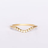 A dainty, yellow gold contour wedding band set with bezel set diamonds. Top view.
