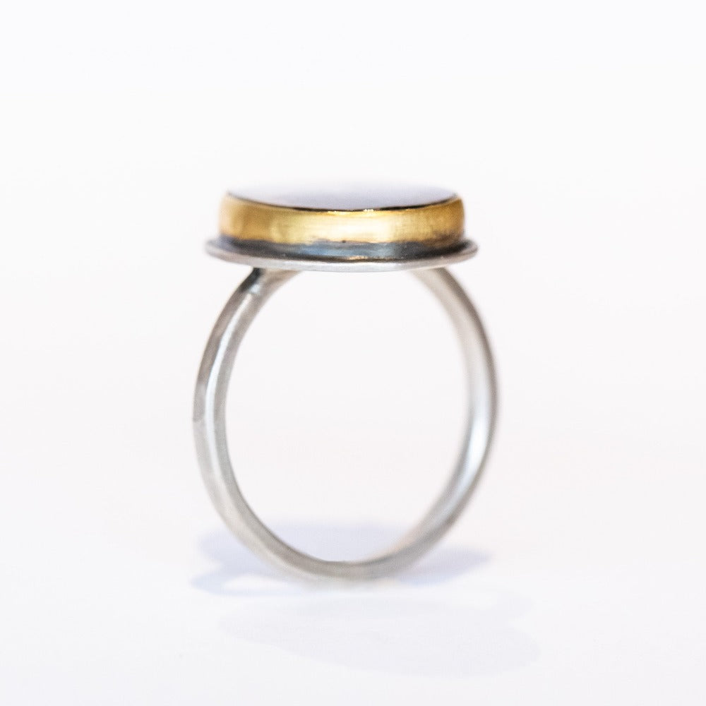 An oval shaped dendritic agate ring with two tiny diamond accents. Set in yellow gold bezel with sterling silver ring. Side view.