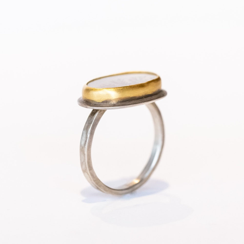 A horizontal oval dendritic agate ring with two diamond accents. Set in yellow gold bezel on a sterling silver ring. Side view.