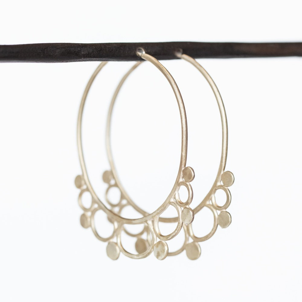 A pair of brushed, hammered silver hoop earrings featuring wire loop and dot filigree accents along the outer edge.
