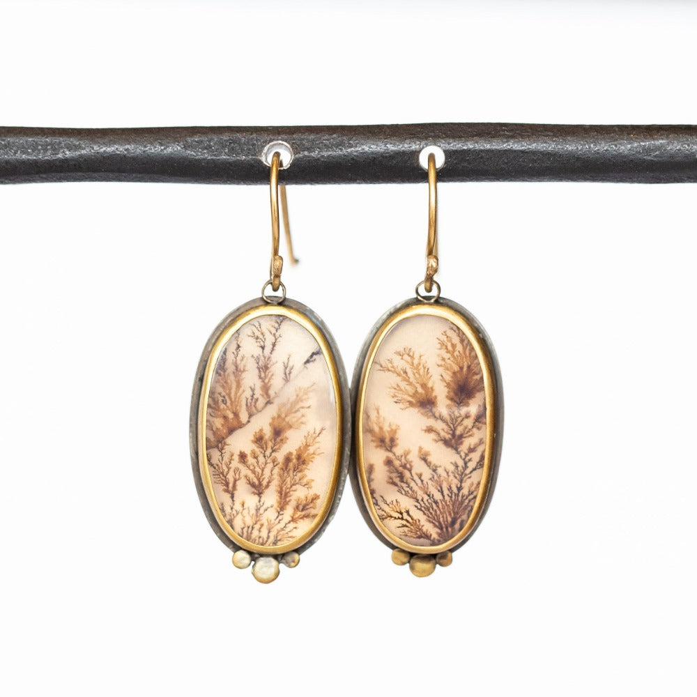 Elongated oval shaped dendritic agate drop earrings with gold dot accents. Set in yellow gold bezels on sterling silver backs.