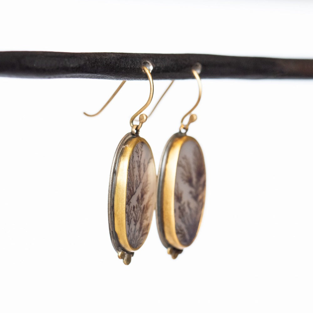 Elongated oval shaped dendritic agate drop earrings with gold dot accents. Set in yellow gold bezels on sterling silver backs.