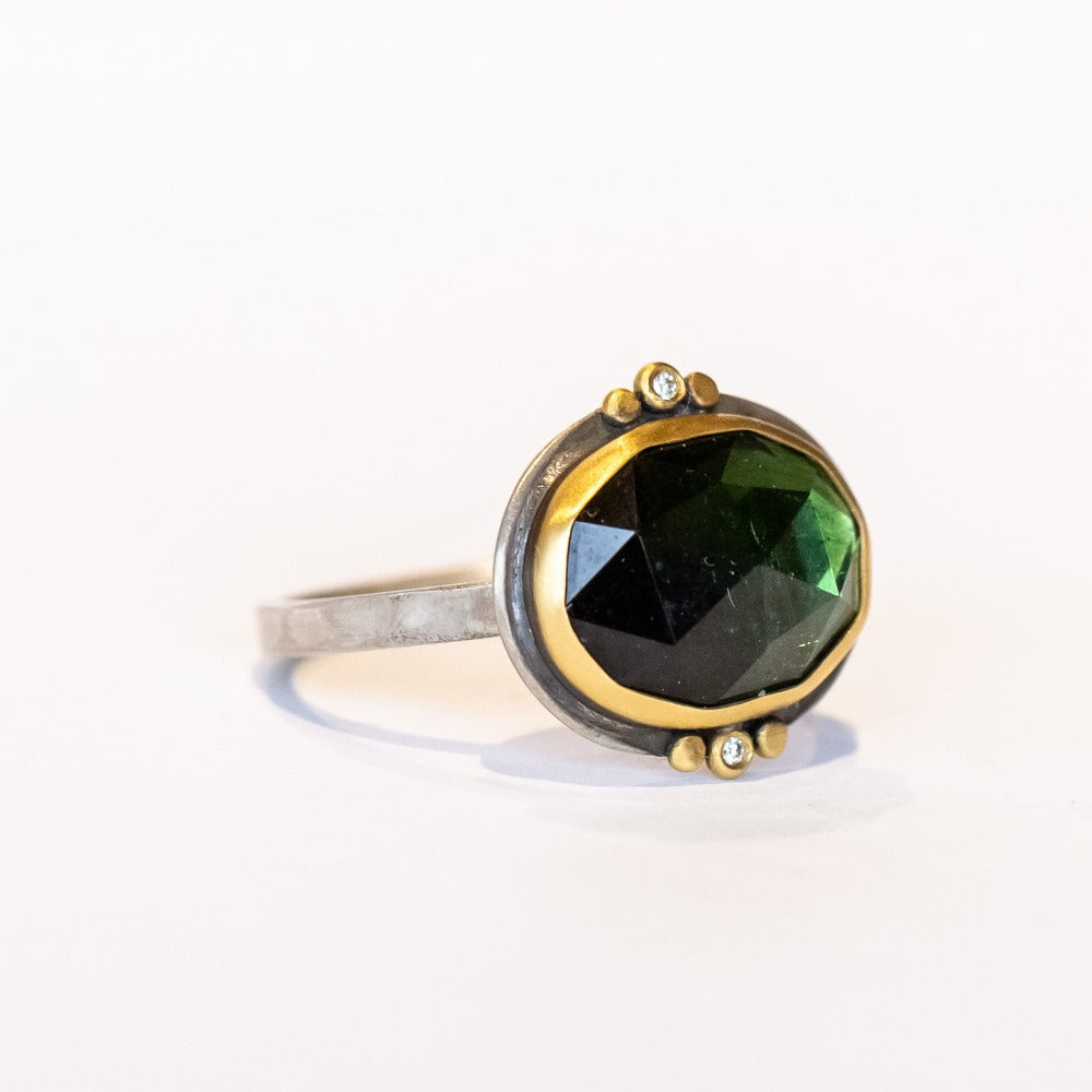 This one-of-a-kind Ananda Khalsa gemstone ring features a deep green oval rose cut tourmaline accented by tiny diamonds and 22k yellow gold dot accents set in a sterling silver ring.