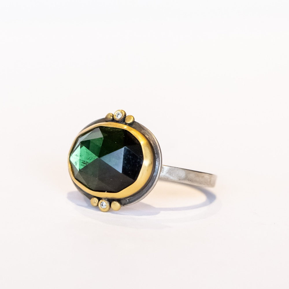 This one-of-a-kind Ananda Khalsa gemstone ring features a deep green oval rose cut tourmaline accented by tiny diamonds and 22k yellow gold dot accents set in a sterling silver ring.