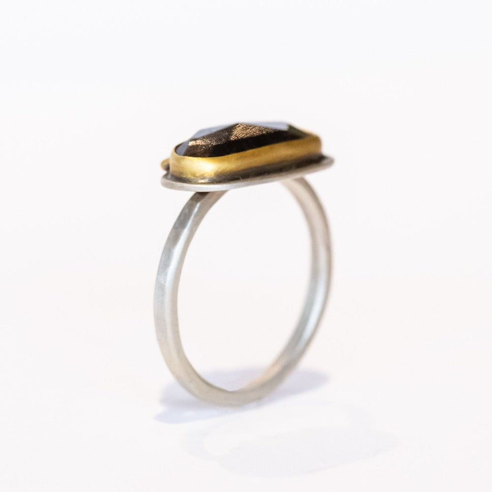 An elongated, rose cut labradorite gemstone in deep blue is set horizontally on this sterling silver ring. The gem is surrounded in a yellow gold bezel and accented along one edge with five petite diamonds.