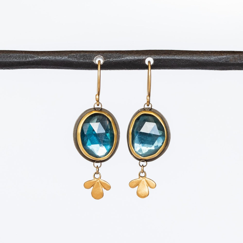 Oval rose cut London Blue Topaz gemstones are bezel set in yellow gold with sterling silver backs, with petite leaf-shaped gold dangles in these Ananda Khalsa drop earrings.
