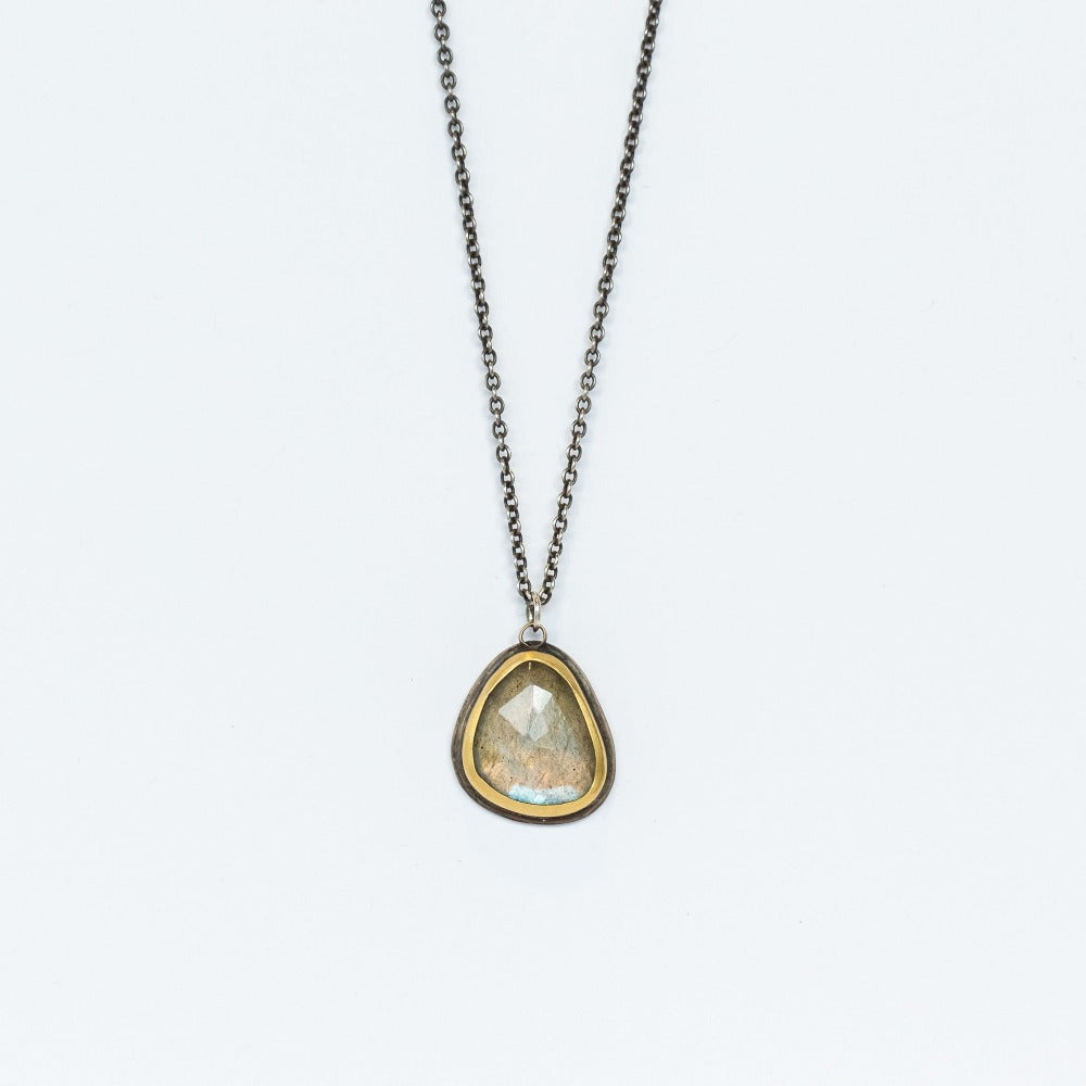 An asymmetrical rose cut labradorite gemstone is set in a yellow gold bezel on sterling silver back, suspended from a blackened silver cable chain in this Ananda Khalsa necklace.