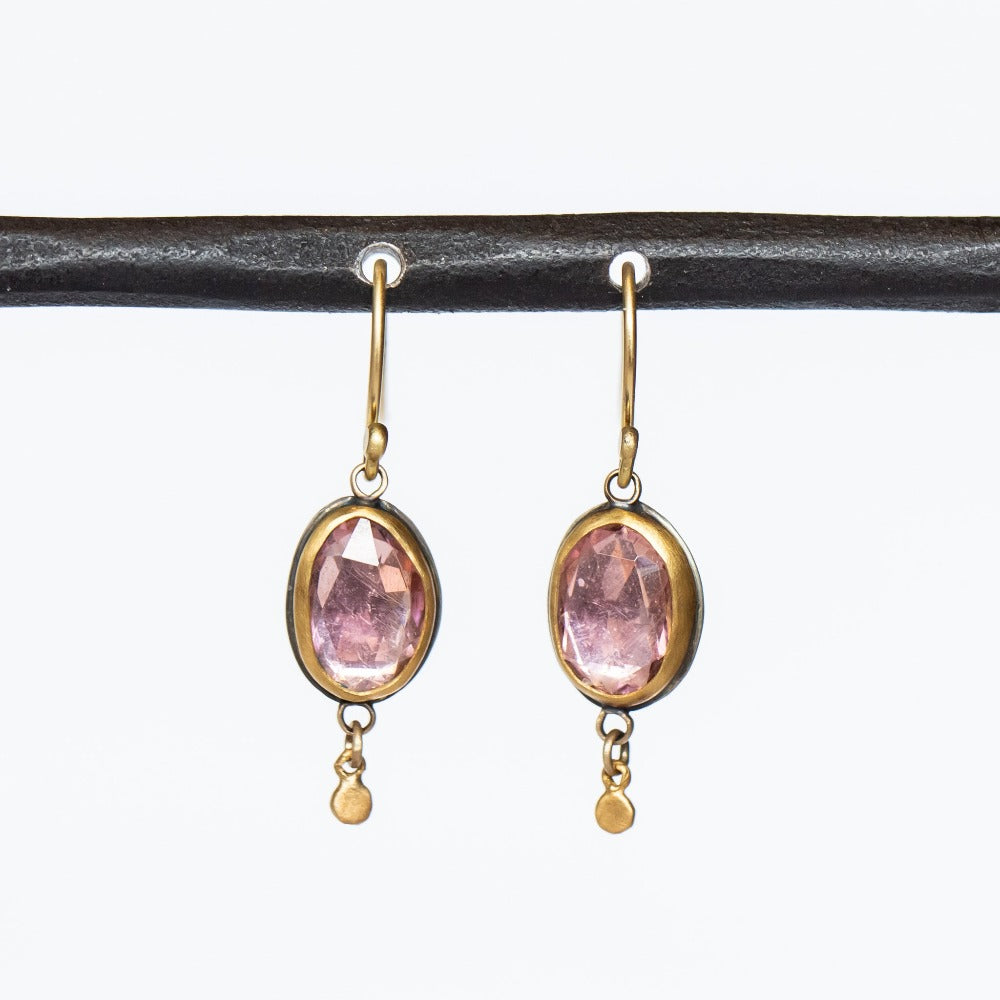 Rose cut, oval shaped pink tourmaline gemstones are bezel set into these Ananda Khalsa earrings. The bezels and dainty dot drops at the bottom are yellow gold, and the backings are sterling silver.