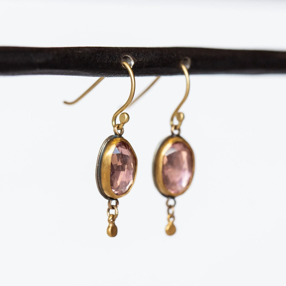 Rose cut, oval shaped pink tourmaline gemstones are bezel set into these Ananda Khalsa earrings. The bezels and dainty dot drops at the bottom are yellow gold, and the backings are sterling silver.