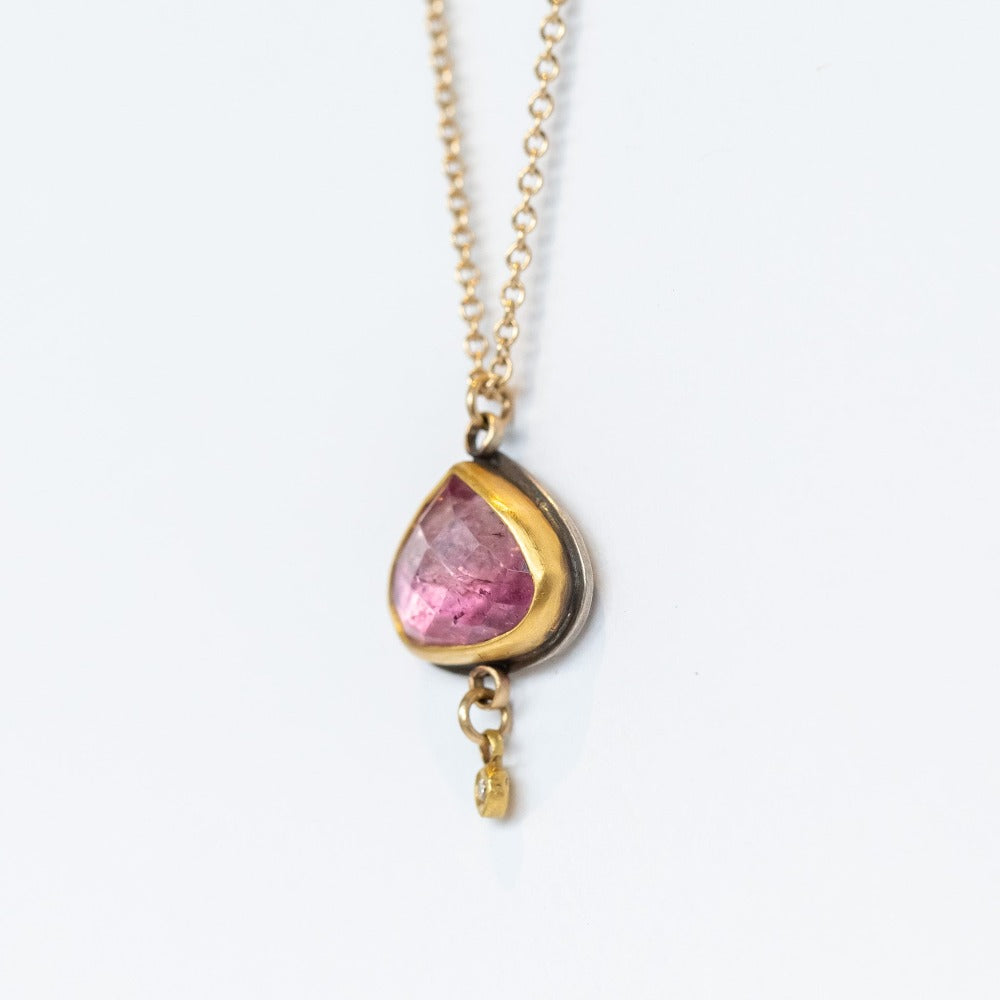 A yellow gold chain necklace with a wide teardrop, rose cut pink tourmaline in a 22k yellow gold bezel backed by oxidized sterling silver. A tiny bezel-set diamond charm dangles freely from the base.